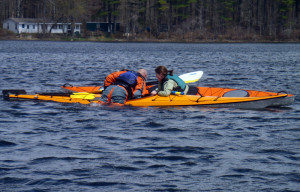 Student Amy Fullerton assists instructor Vaughan Smith as he demonstrates how to get back into a kayak after a wet exit. (EasternSlopes.com)